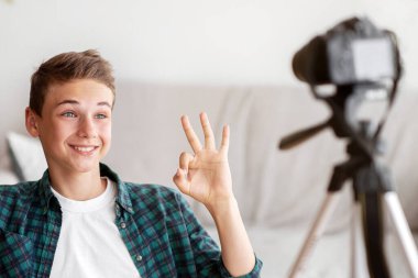 Olumlu genç çocuk evden yayın yapıyor, kameraya iyi bir hareket gösteriyor.