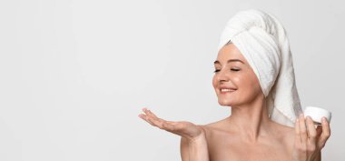 Cilt Gençleştirme Konsepti. Güzel Olgun Kadın Nemlendirici Krem Tutarken ve Uygularken Portresi, Boş Alanı Olan Gri Arkaplanda Duruyor