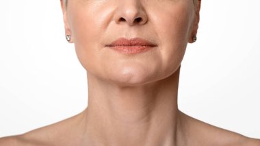 Yaşlanma karşıtı cilt bakımı. Güzel ciltli, açık arkaplan, yakın plan, orta yaşlı kadın portresi.