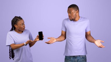 Başka bir Life Online, Aldatma Konsepti. Kızgın siyah kadın erkek arkadaşının cep telefonunu kontrol ediyor, kışkırtıcı mesajlar gösteriyor ve ondan açıklama istiyor, adam ellerini açıyor, Violet stüdyo geçmişi var.