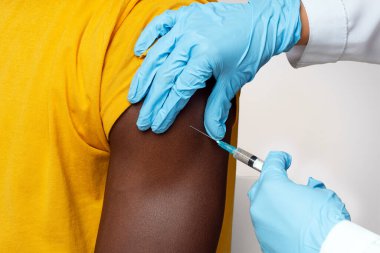 Aşı Süreci. Siyah Erkek Hastaya Tanımlanamayan Doktor Mavi Eldivenli Tıp İşçisi Afro-Amerikan Erkek Koluna Şırınga sokuyor Kesik Görüntü, Yakın Çekim