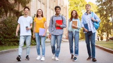 Dışarıdaki üniversite binasının yakınındaki kameraya gülümseyen çok ırklı öğrenci grubu. Üniversite Eğitimi Konsepti