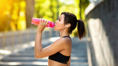 Afrikalı sporcu kadının su içişi, parkta sabah eğitimi, yakın çekim...