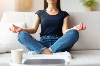 Tanımlanamayan bir kadın Lotus pozisyonunda meditasyon yapıyor evdeki koltukta dinleniyor. Haftasonu Gevşemesi. Kırpılmış, Seçici Odaklanma