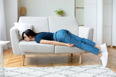 Yorgunluk. Yorgun bir kız, evde dinlenirken günün sonunda yorgun bir şekilde kanepede yatıyor..