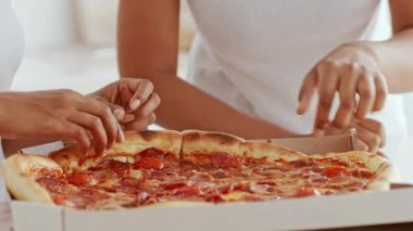 İki kız kardeş evde sıcak bir anı paylaşıyor. Lezzetli bir pizza eşliğinde kaynaşıyorlar. Yakın ilişkileri aile toplantılarının tipik sıcaklığını ve sevgisini yansıtır..