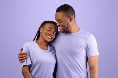 Mutlu Sevgili Çift Konsepti. Romantik siyahi adamın sevgilisini kucakladığı, kollarına aldığı, mor menekşe stüdyosunun arka planında izole bir şekilde dikildiği, beleş fotokopi alanı.