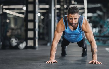 Spor salonunda konsantre kaslı adam eğitimi, itme egzersizleri yapıyor, boş alan