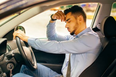 Araba kazası konsepti. Üzgün Arap işadamı, ön koltukta oturuyor ve başına dokunuyor, araba kazası geçiriyor. Ortadoğulu adam uçağa geç kalıyor, trafiğe takılıp kalıyor, yandan bakıyor.