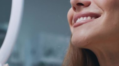 Genç bir kadın dişçi koltuğunda otururken gülümsüyor. Dişçi rutin bir check-up için hazırlanıyor, rahat bir ortam sağlıyor. Klinikte temiz ve modern bir tasarım sergileniyor.