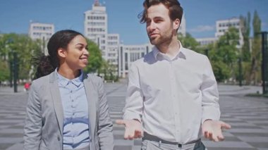 Bir erkek ve bir kadın, her ikisi de girişimci, açık havada canlı bir sohbete girişiyor. İş kıyafetleri giyiyorlar, günışığında yürürken kurumsal bir çevrede fikirleri tartışıyorlar..