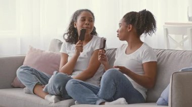 İki Afrikalı Amerikalı kız kardeş evlerinde rahat bir kanepede dondurma yerken aynı neşe ve kahkahayı paylaşıyorlar. Gülüşleri sevgiyi ve kardeşliği yansıtıyor. Sıcak, davetkar bir yerde..