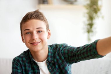 Evde tek başına vakit geçirirken selfie çeken yakışıklı çocuk sosyal medyada paylaşıyor, gençlik hayatı sürüyor.