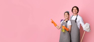 Temizlik servisi reklamı. Önlüklü mutlu bir milenyum çifti, ellerinde ev malzemeleri ve pembe arka plandaki fotokopi alanını işaret ediyor.