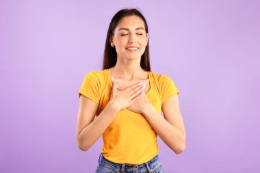 Minnet kavramı. Etkilenmiş, dost canlısı, gözleri kapalı, ellerini göğsünde tutan, iltifatın dokunduğu bir kadın.