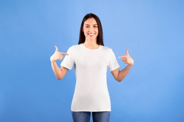 Beni seç. Metnin ya da promosyon içeriğin için boş beyaz tişörtündeki fotokopi alanını gösteren pozitif kadın