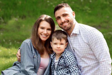 Sevimli bir çocuk ve ailesi kırsalda piknikte güneşli bir yaz gününün tadını çıkarıyorlar.