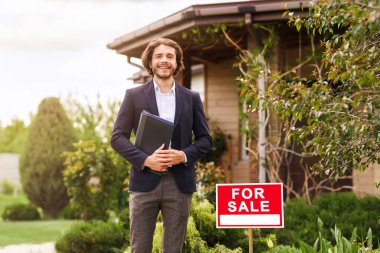 Satılık yeni evin önünde duran mutlu emlakçı. Açık havada. Boşluğu kopyala