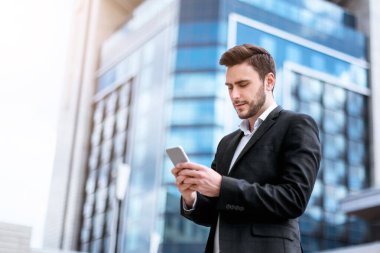 Şehir merkezindeki akıllı telefondan internette gezinen ciddi genç girişimci.