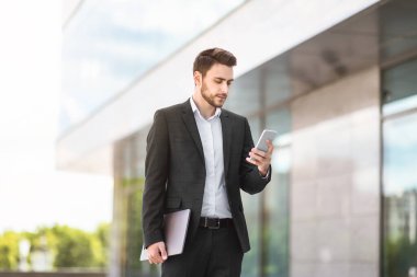 Şehir sokaklarında internet kullanan cep telefonu ve tablet bilgisayarı olan yakışıklı bir işletme yöneticisi