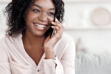 Memnun oldum. Neşeli Afro-Amerikalı kız evde cep telefonuyla konuşuyor arkadaşlarıyla telefon görüşmesi yapıyor, mekanı kopyalıyor.
