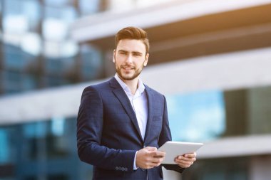 Milenyum işletme müdürü şehir merkezindeki idari binanın yanında tablet kullanıyor