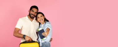 Sevimli, genç İspanyol çift birlikte tatile çıkıyorlar, bavullarını taşıyorlar, mutlu adam ve kadın uçak bileti ve pasaport taşıyorlar, pembe arka plan. Yaz tatili, gezi.