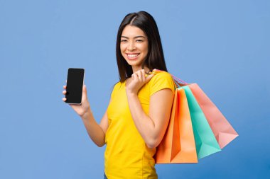 Çevrimiçi Alışveriş Konsepti. Alışveriş Torbalı Mutlu Asyalı Kız Siyah Akıllı Telefon Ekranı Gösteriyor, Kopya Boşluğu ile Model Görüntü