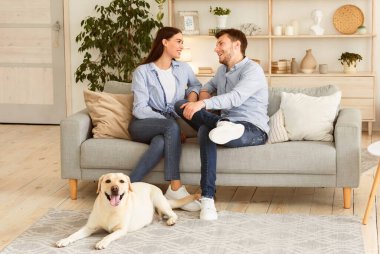 Yurtiçi Atmosfer Konsepti. Kanepede oturan iki kişinin portresi, yerde yatan labrador.