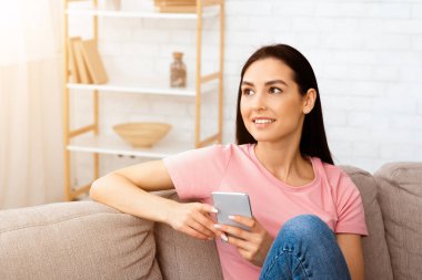 Aramanı ya da mesaj bırakmanı bekliyorum. Hayalci milenyum kadını oturma odasında rahat bir koltukta oturuyor uzaktan bakıyor düşünüyor ya da hayal ediyor, akıllı telefonu tutuyor ve dalgın dalgın dalgın hayaller kuruyor.