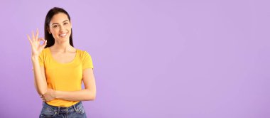 Her şey yolunda. Mutlu kadın portresi el ve parmaklarıyla onay hareketi yapıyor, gülümsüyor, iyi olduğunu gösteriyor, mor stüdyo arka planında soyutlanmış. Kendine güveni tam bir bayan.