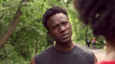 Atletik bir adam halka açık bir parkta durur, antrenmanına konsantre olur, diğer adama bakar. Bereketli çevre ve yürüyüş yolu parlak bir günde sağlıklı bir açık hava yaşam tarzını gösteriyor..