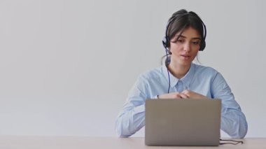 Genç bir kadın evindeki öğrencilere bilgisayar kullanıyor ve kulaklık takıyor. Uzaktan eğitim alıyor, modern öğretim yöntemleri gösteriyor..