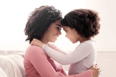 Annemle bağ kuruyorum. Mutlu Hamile Kadın 'ın evde küçük kızıyla kucaklaşırken, pencerenin önünde kanepede otururken,