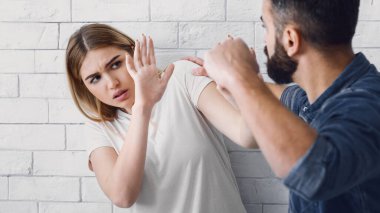 Kavga, şiddet ve koca evde karısını dövüyor. Kızgın adam korkmuş kadına yumruk kaldırır, kadın ellerini, panorama, kopyalama alanı ile kaplar.