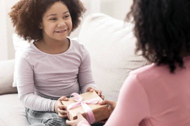 Anneler Günün kutlu olsun. Sevgi dolu annesine hediye kutusunu veren küçük tatlı afro kız, siyah kız, anneyi şu anda evde seçici ve seçici bir şekilde selamlıyor.