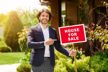 Kendine güveni tam bir emlakçı. Dışarıdaki güzel binanın önünde satılık bir ev var.