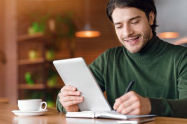 Girişimci gününü kafede kahve içerken, not alırken, dijital tablet kullanırken, boş alan kullanırken planlar yapıyor.