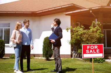 Ev temsilcisi dışarıda potansiyel alıcılara yeni bir mülk gösteriyor. Boşluğu kopyala