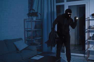 Soygun Konsepti. Dairede ya da ofiste duran, el feneri kullanan, çalacak bir şey arayan gizli bir hırsız.