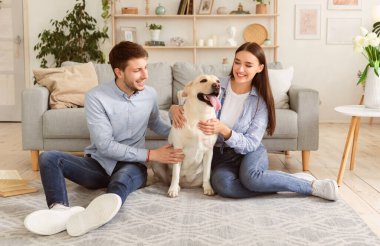 Hafta sonu evde. Neşeli oğlan ve kız oturma odasında labradorlarıyla oynuyorlar, yerde dinleniyorlar.