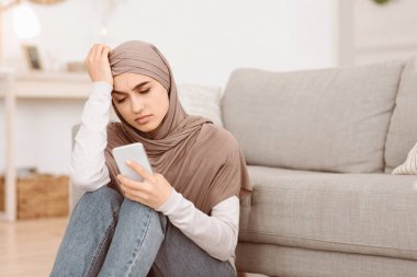 Hoş olmayan bir mesaj. Depresyondaki Arap Kız Evde oturup Akıllı Telefon Ekranına, Boş Alan 'a Bakıyor