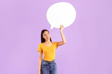 İyi fikir kavramı. Beyaz boş konuşma balonu tutan düşünceli bir kadının dikey portresi, düşünmek ve bakmak, duyuru için boş bir alan, mor stüdyo arka plan duvarı üzerinde izole edilmiş.