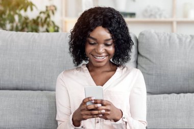 Evde boş zaman. Mutlu Siyah Kadın Akıllı Telefon ve Çay Salonunda Dinleniyor, Anlaşıldı