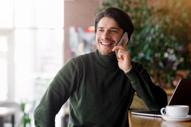 Zengin girişimci, kafede dizüstü bilgisayarla çalışırken akıllı telefonla konuşuyor, boşluğu kopyalıyor.