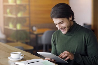 Başarılı bir iş adamı kafeteryada gününü dijital tablet kullanarak, notlar alarak, boş bir alanda geçirir.