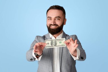 Mutlu milenyum girişimcileri mavi arka planda 100 dolarlık banknot gösteriyor.