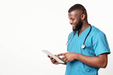 Genç Afrikalı Amerikalı cerrah dijital tablet kullanarak beyaz stüdyo arka planında, kopyalama alanı kullanıyor