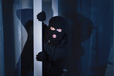 Suç kavramı. Maskeli soyguncu açık cam bir kapı ya da pencereden evi gözetliyor, boşluğu kopyala