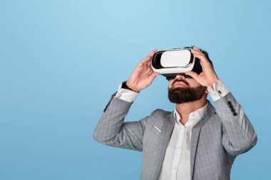 Sanal gerçeklik kulaklığı takmış iş adamı mavi arka planda siber uzayı keşfediyor